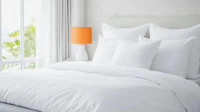 Modern Bedroom Interior With White Bedding And Orange Lamp
