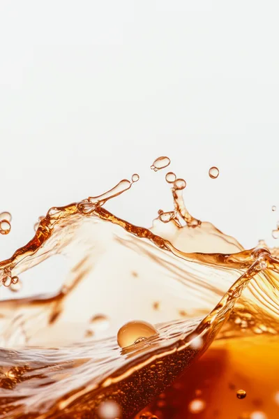 Dynamic Splash Of Amber Liquid Against White Background