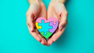 Hands Holding A Colorful Heart Puzzle
