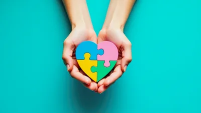 Hands Holding A Colorful Heart Shaped Puzzle