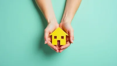 Hands Holding A Yellow Paper House Cutout