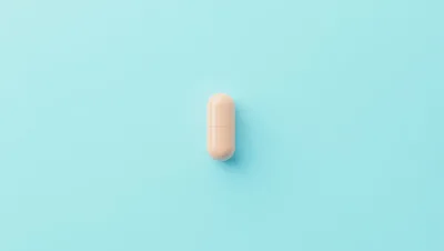 Single Beige Medical Capsule On Light Blue Background