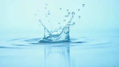 Water Crown Splash With Droplets On Blue Background