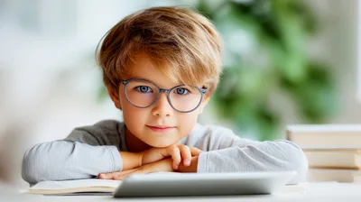 Young Boy Wearing Glasses Studying With Tablet