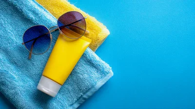 Sunglasses And Sunscreen On Blue And Yellow Towels