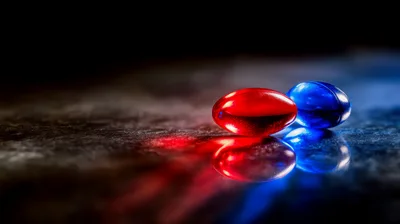 Red and Blue Gel Capsules on Reflective Surface