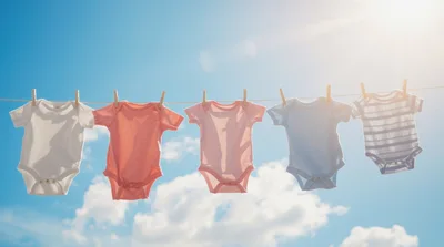 Baby Onesies Hanging on a Clothesline Against Blue Sky