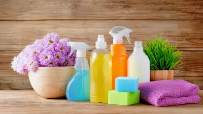 Cleaning Supplies With Flowers And Towel On Wooden Table