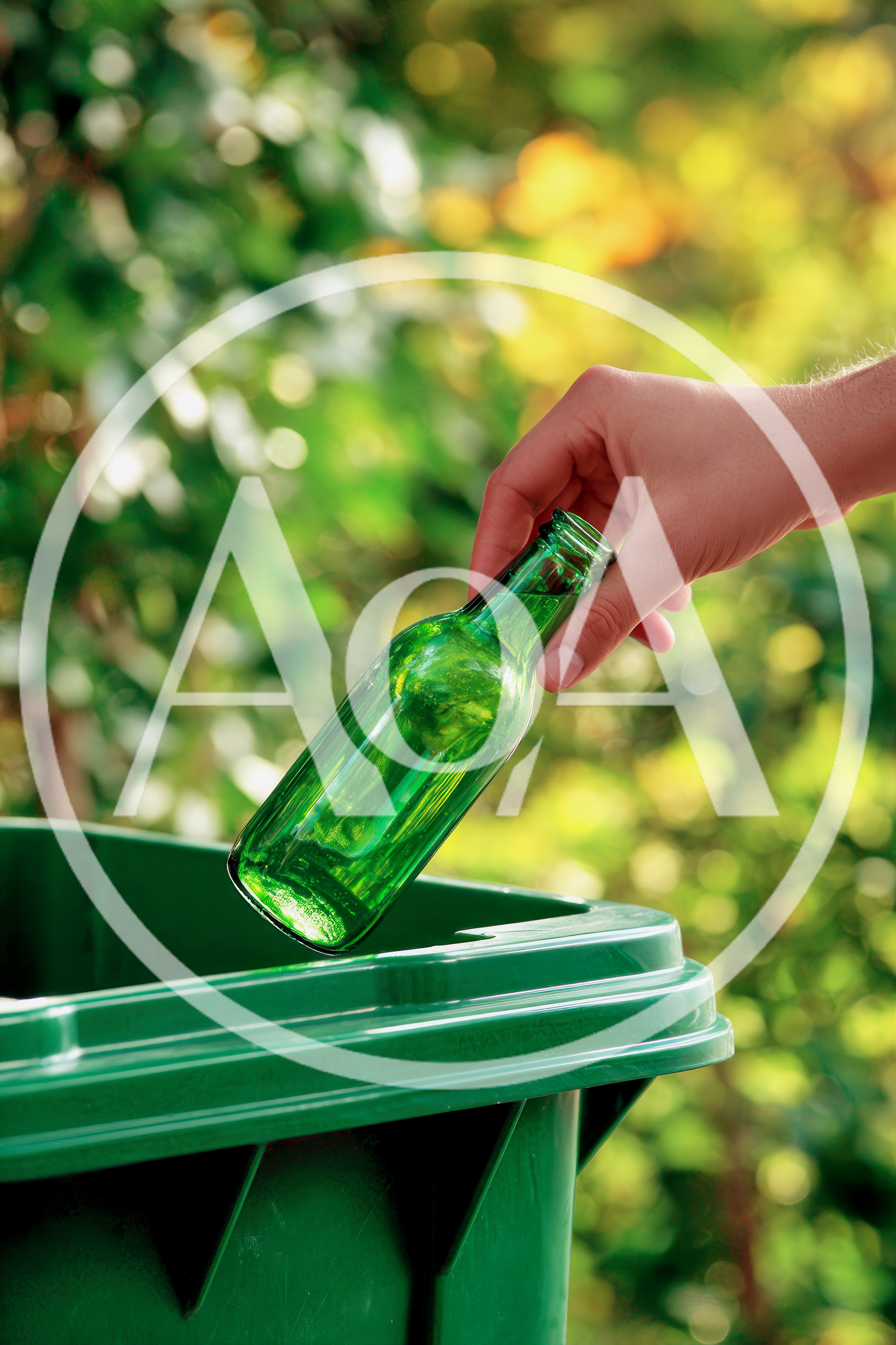 Hand Placing Green Glass Bottle Into Recycling Bin
