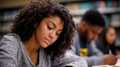 Young Woman Studying Diligently In A Library Setting