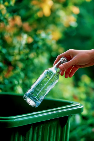 Hand Placing Glass Bottle Into Recycling Bin