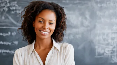 Smiling African American Female Teacher Standing In Classroom