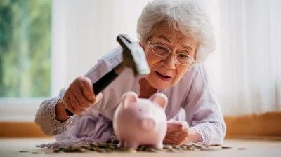 Senior Woman About To Break Piggy Bank With Hammer
