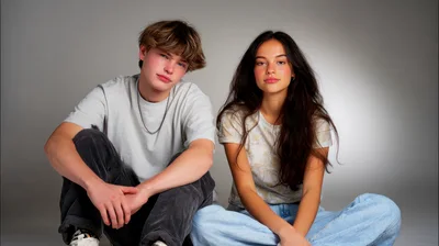 Young Couple Sitting Together In Studio Portrait