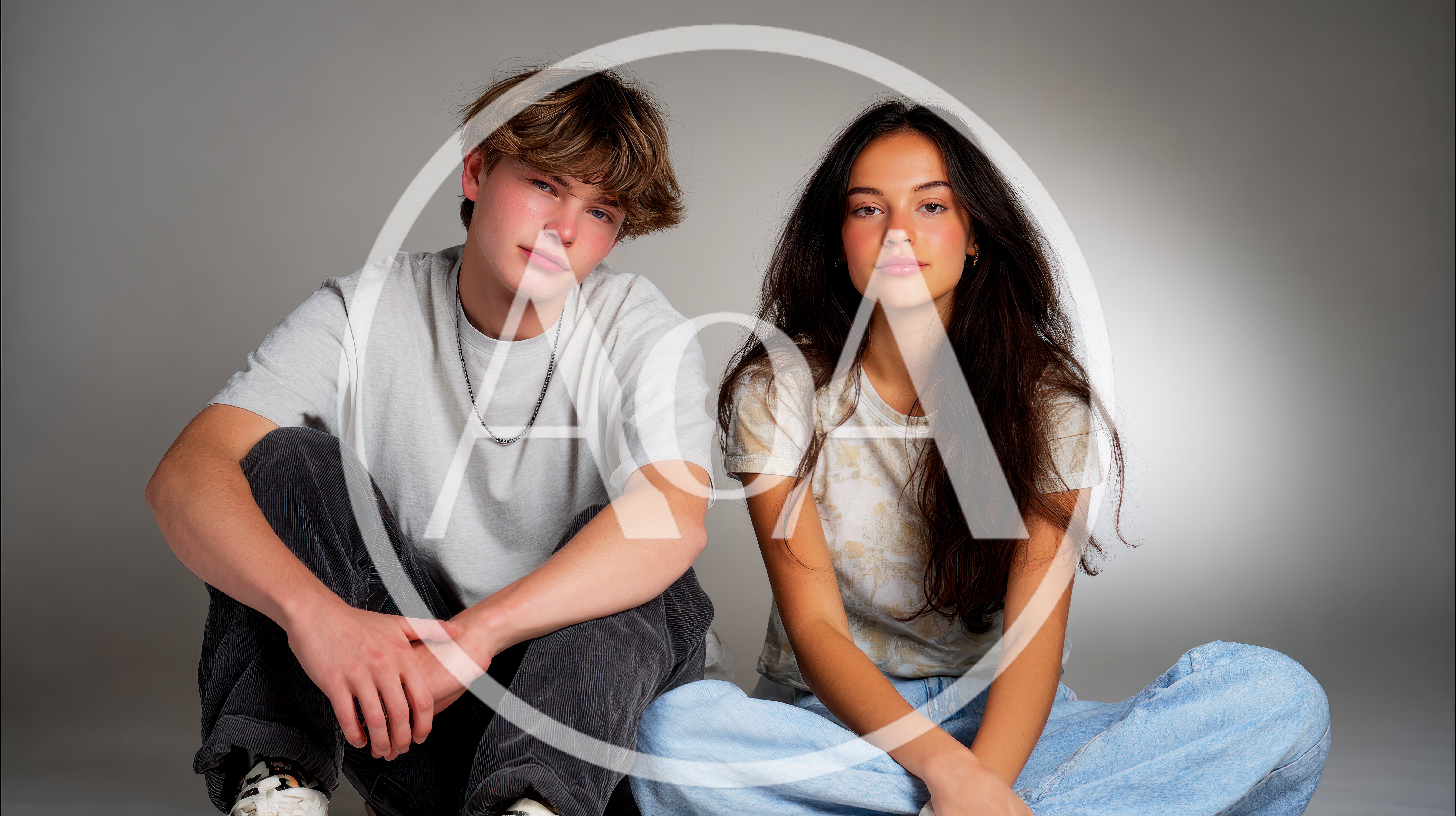 Young Couple Sitting Together In Studio Portrait