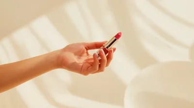 Hand Holding A Lipstick Tube In Soft Sunlight