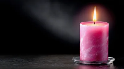 Pink Pillar Candle Burning on a Dark Surface