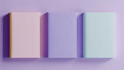 Three Pastel Colored Books On A Purple Background