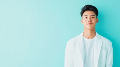 Young Asian Man Wearing White Blazer Against Teal Background