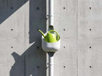 Green Watering Can Resting In A Rainwater Downspout