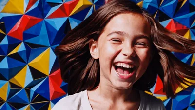 Happy Young Girl Laughing In Front Of Geometric Background