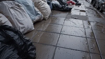 Rain Falling On Pavement With Piled Trash Bags