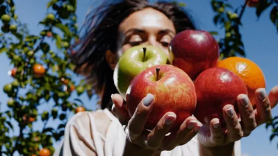 Young Woman Holding Fresh Fruit In Orchard