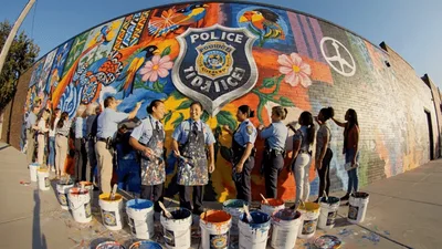 Police Officers And Community Members Painting A Mural Together