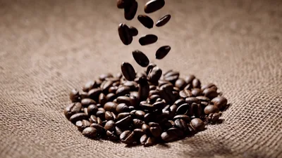Roasted Coffee Beans Falling Onto Burlap Fabric