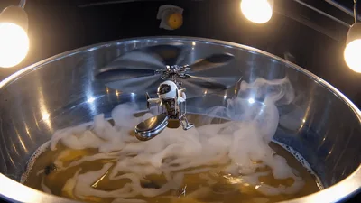 Miniature Helicopter Toy Hovering Over Bubbling Liquid