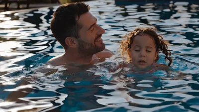 Father Teaching Young Daughter To Swim In Pool