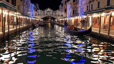 Gondolas Floating Through Illuminated Venetian Canal at Night