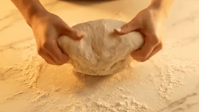 Baker Kneading Dough On A Marble Surface