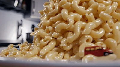 Toy Cars Driving Through A Pile Of Macaroni And Cheese
