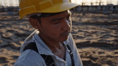 Construction Worker Pushing Wheelbarrow On Sandy Site