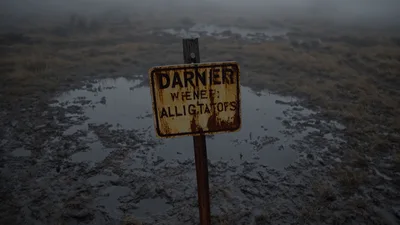 Rusty Warning Sign Standing In A Foggy Marshland