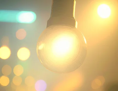 Glowing Incandescent Light Bulb Against Blurred City Lights