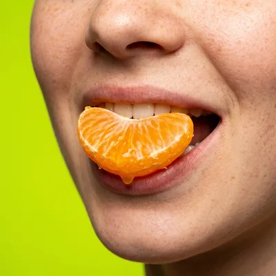 Close Up Of A Woman Eating A Mandarin Orange Segment