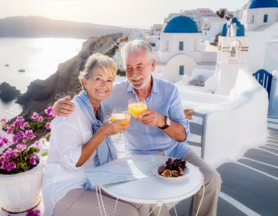 Senior Couple Toasting With Orange Juice In Santorini