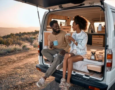 Couple Enjoying Coffee Inside A Camper Van At Sunset