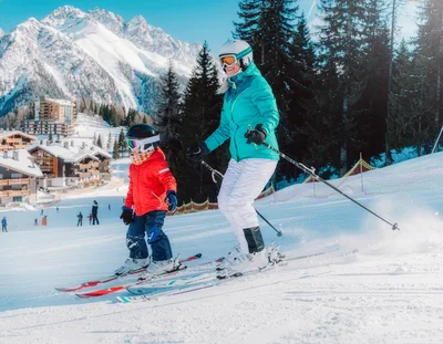 Mother and Child Skiing Together on Sunny Mountain Slope