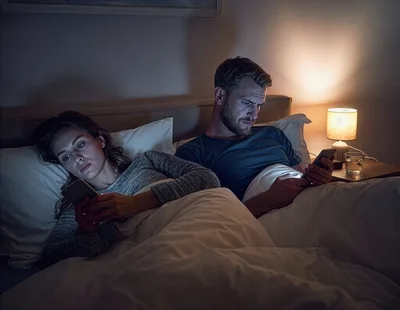 Couple Using Smartphones In Bed At Night