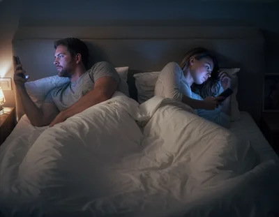 Couple Using Smartphones In Bed At Night