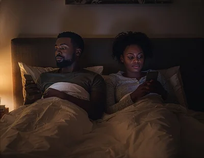 Couple Using Smartphones In Bed At Night