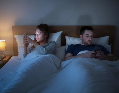 Couple Using Smartphones In Bed At Night