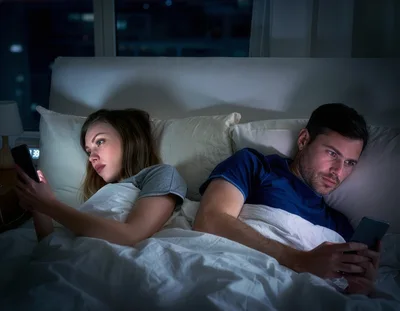 Couple Using Smartphones In Bed At Night