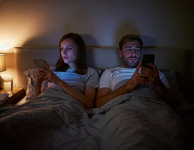 Couple Using Smartphones In Bed At Night