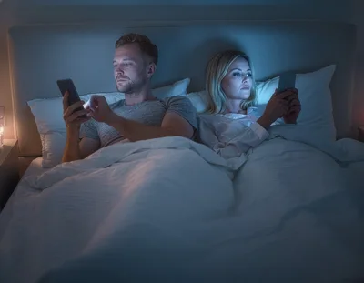 Couple Using Smartphones In Bed At Night