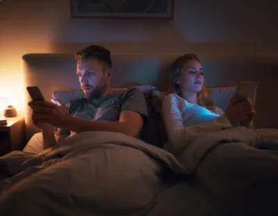 Couple Using Smartphones In Bed At Night