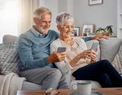 Senior Couple Using Smartphones Together on Sofa